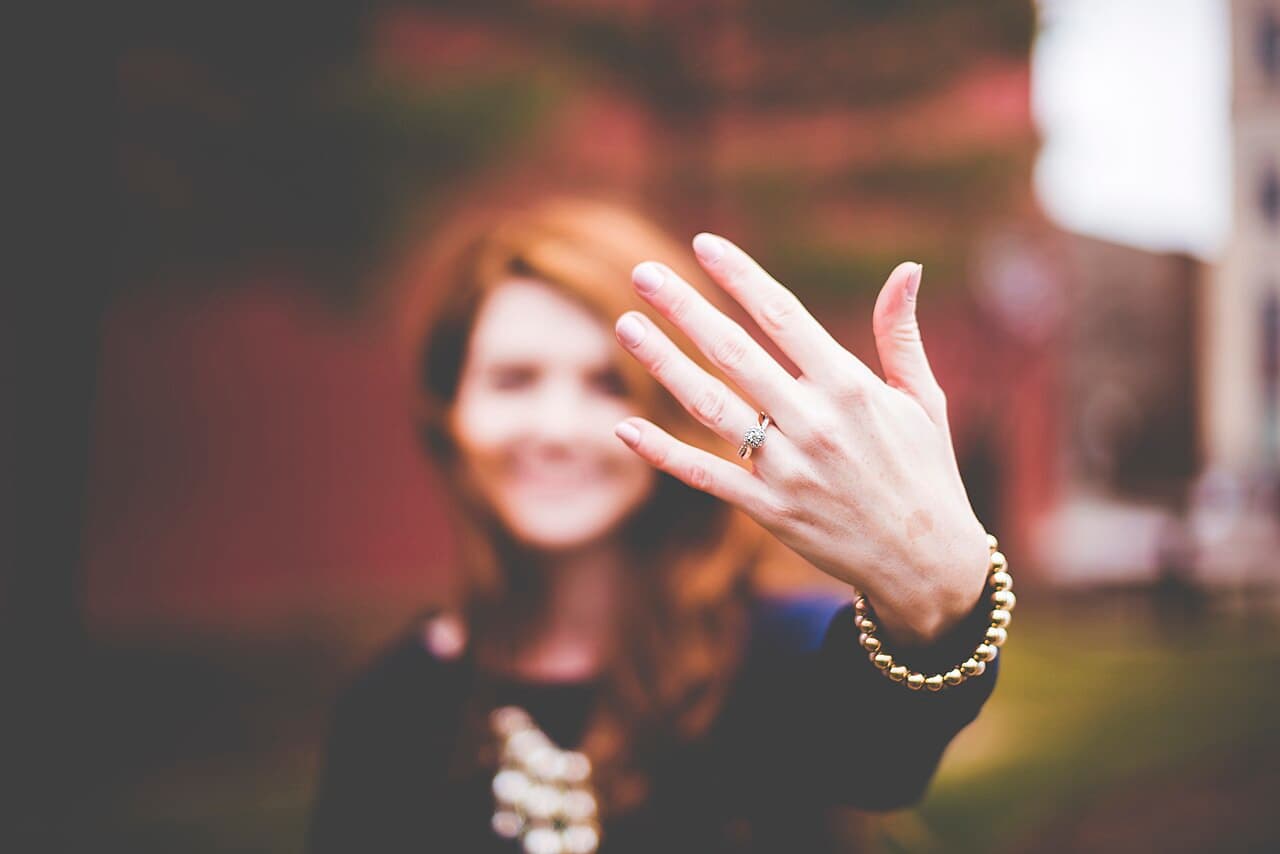 An engagement ring on a raised hand